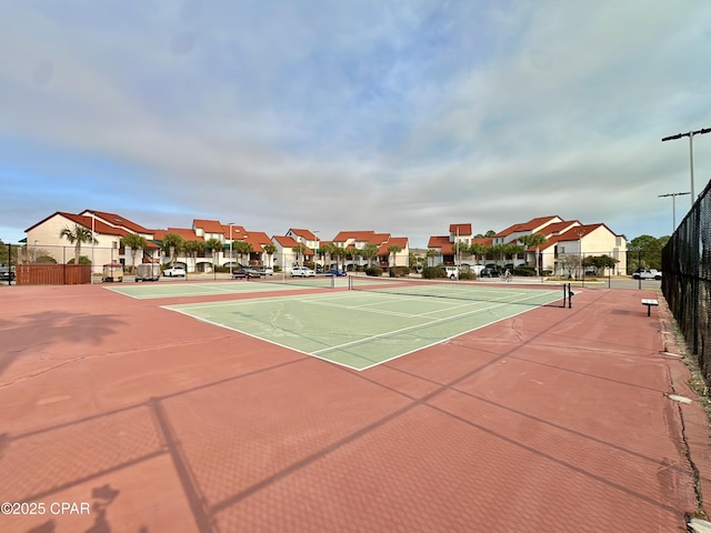 view of tennis court with fence and a residential view