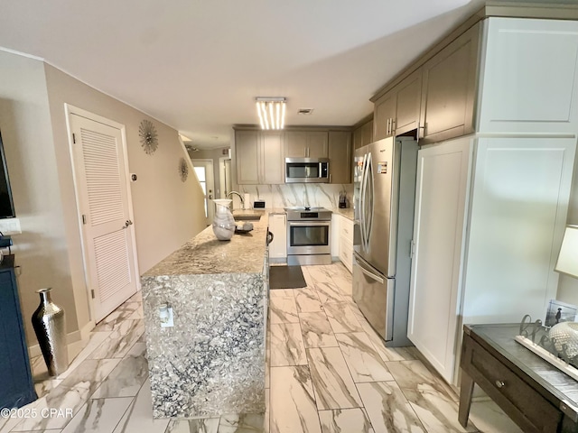 kitchen with stainless steel appliances, marble finish floor, decorative backsplash, and light countertops