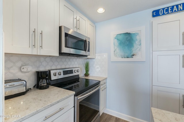 12011 Front Beach Rd Unit 204B, Panama City Beach, FL 32407 - kitchen with stainless steel appliances, white cabinets, light stone countertops, backsplash, and dark wood-style flooring