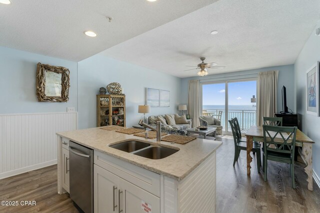 12011 Front Beach Rd Unit 204B, Panama City Beach, FL 32407 - kitchen featuring a sink, stainless steel dishwasher, dark wood finished floors, a wainscoted wall, and a textured ceiling