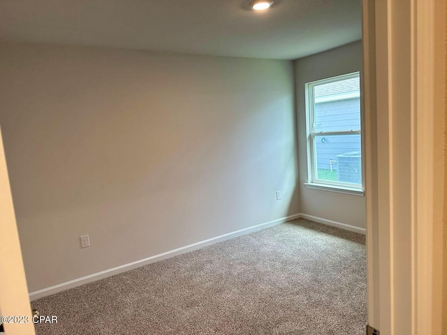 spare room featuring carpet floors and baseboards