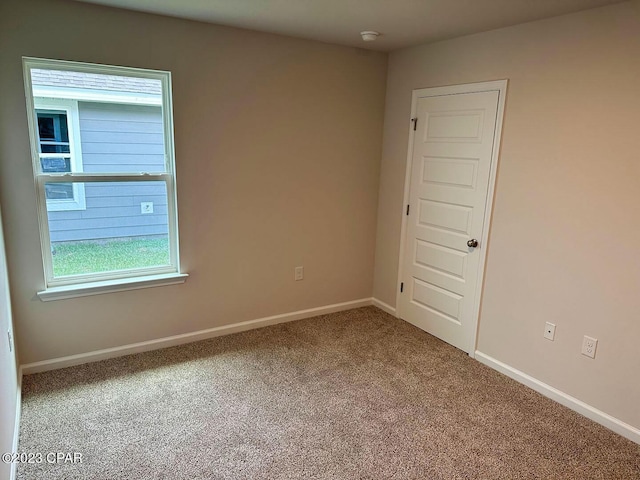 carpeted empty room featuring baseboards