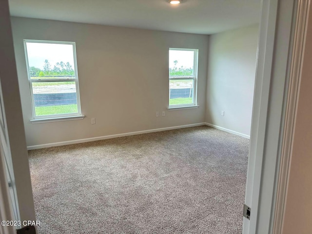 unfurnished room featuring carpet and baseboards