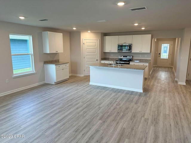 kitchen with white cabinets, appliances with stainless steel finishes, visible vents, and light wood-style floors