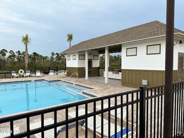 pool featuring an outdoor structure, a patio area, fence, and area for grilling