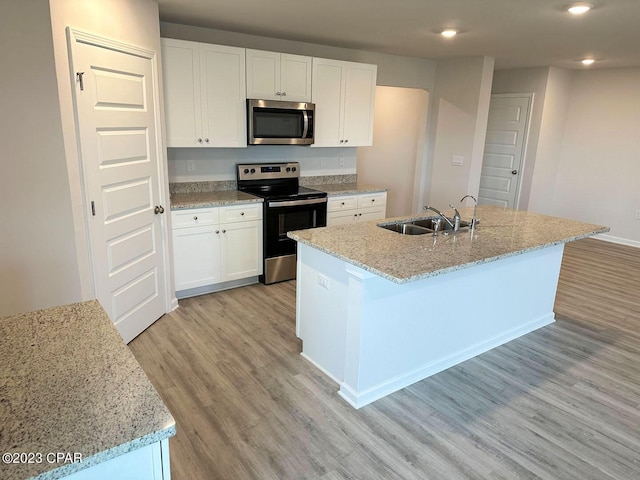 kitchen with appliances with stainless steel finishes, white cabinetry, a sink, and light wood finished floors