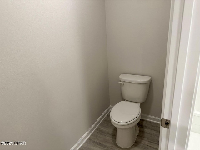 bathroom with toilet, baseboards, and wood finished floors