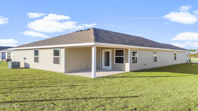 rear view of house with a yard, a shingled roof, a patio area, and central air condition unit