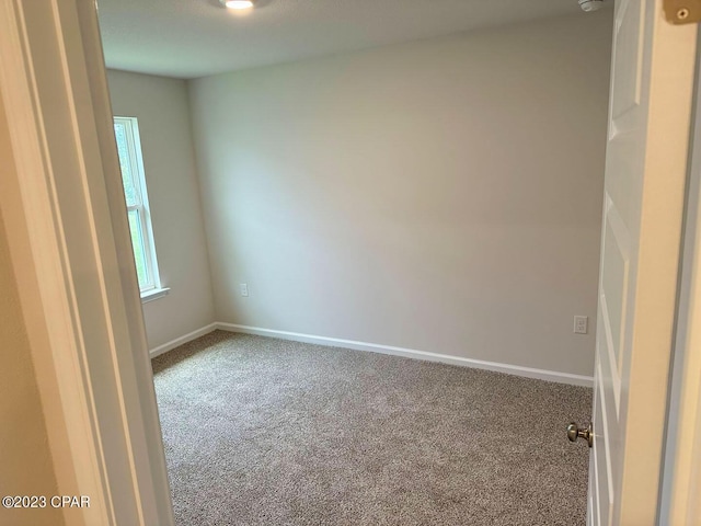 spare room featuring carpet and baseboards