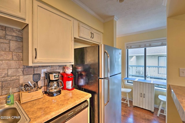 kitchen featuring dark wood finished floors, appliances with stainless steel finishes, ornamental molding, light countertops, and a textured ceiling