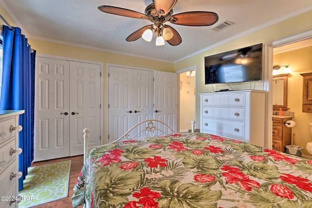 bedroom featuring ceiling fan, wood finished floors, visible vents, multiple closets, and crown molding