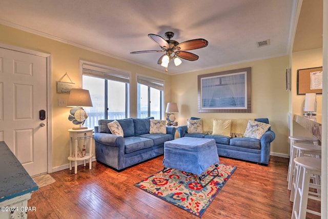 living area with baseboards, wood finished floors, visible vents, and crown molding