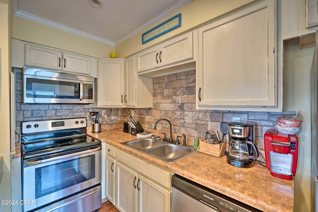 kitchen featuring backsplash, crown molding, stainless steel appliances, and a sink