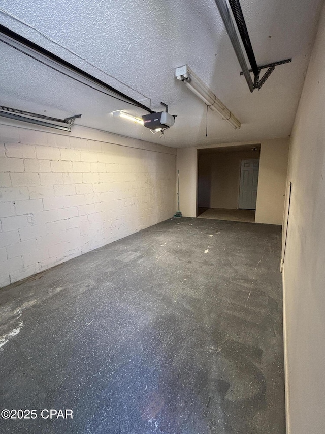 garage with a garage door opener and concrete block wall