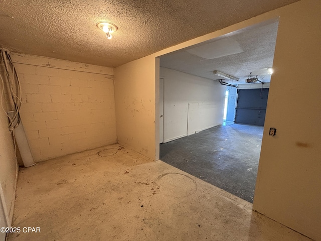 spare room with concrete flooring, a textured ceiling, and concrete block wall