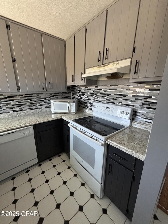 kitchen featuring light floors, tasteful backsplash, a textured ceiling, white appliances, and under cabinet range hood