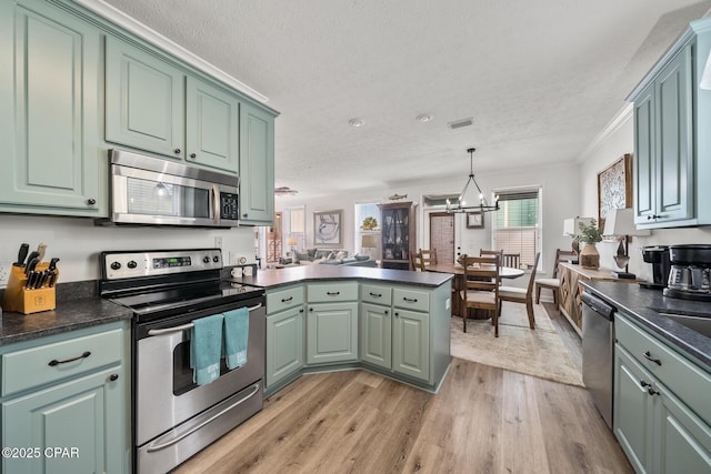 kitchen featuring green cabinets, dark countertops, appliances with stainless steel finishes, and a peninsula