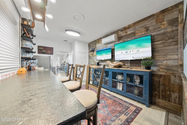 bar featuring a wall mounted air conditioner, wood walls, a sink, and freestanding refrigerator