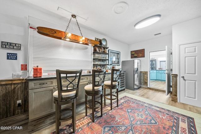 interior space with wood finished floors, dark countertops, visible vents, and stainless steel refrigerator with ice dispenser