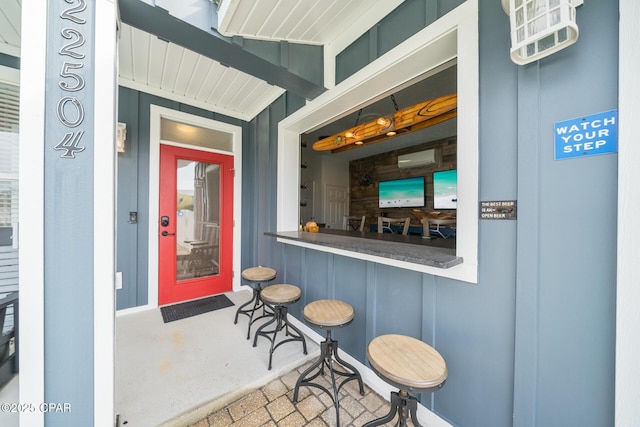 view of exterior entry featuring a wall unit AC and outdoor dry bar