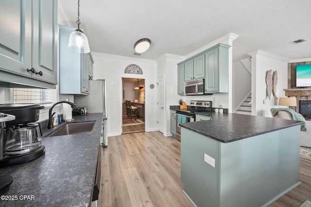 kitchen with visible vents, light wood finished floors, a sink, appliances with stainless steel finishes, and dark countertops