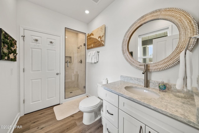 full bath with a shower stall, baseboards, toilet, wood finished floors, and vanity