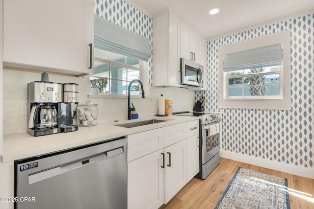 13011 Oleander, Panama City Beach, FL 32407 - kitchen with appliances with stainless steel finishes, a sink, white cabinets, and wallpapered walls