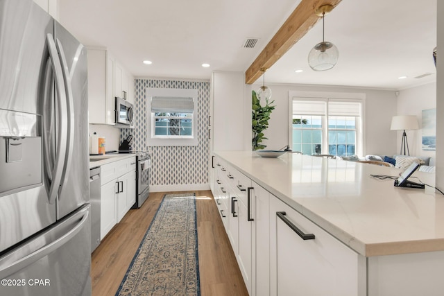 13011 Oleander, Panama City Beach, FL 32407 - kitchen featuring beam ceiling, visible vents, light wood-style flooring, appliances with stainless steel finishes, and wallpapered walls