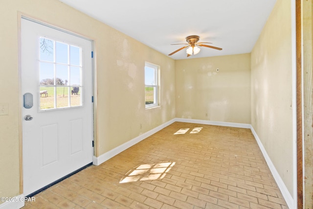 doorway with a ceiling fan, brick floor, and baseboards