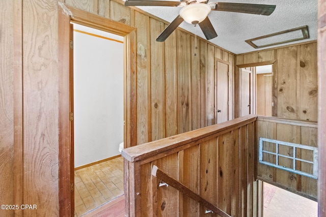 hallway featuring brick floor, wooden walls, and a textured ceiling