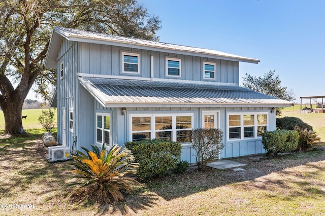 exterior space with board and batten siding, ac unit, and metal roof