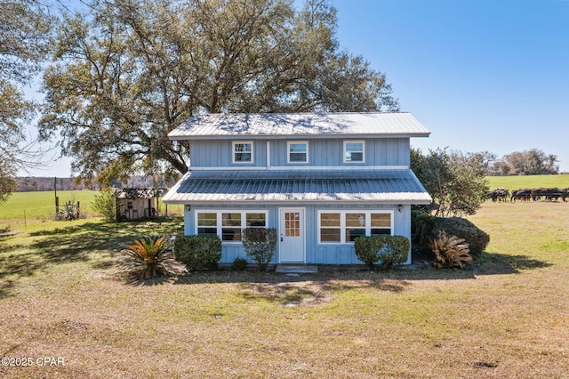 traditional-style house featuring a front lawn and metal roof