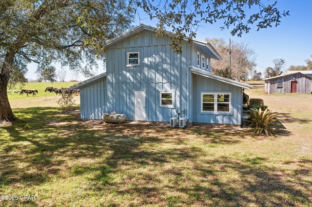 rear view of property featuring board and batten siding and a lawn