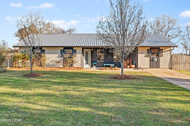 ranch-style house featuring metal roof, a front yard, and fence