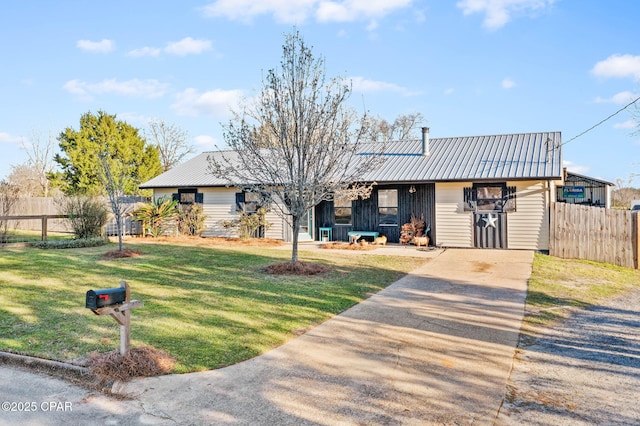 view of front of house with a front yard, fence, and metal roof