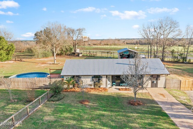 exterior space with metal roof, a rural view, a front yard, and fence