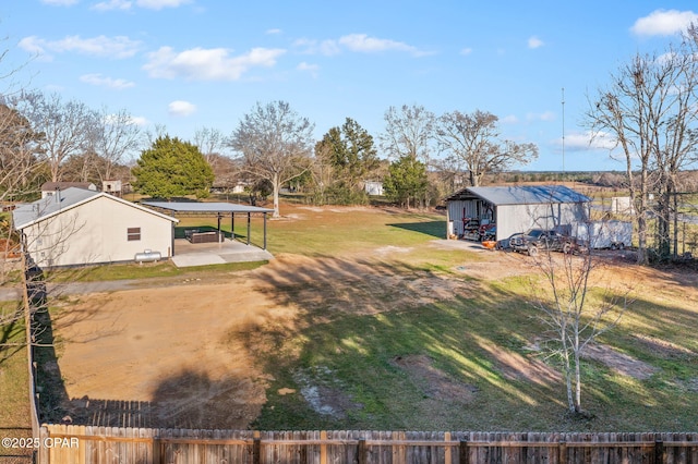 view of yard featuring an outdoor structure, fence, a pole building, and a patio area