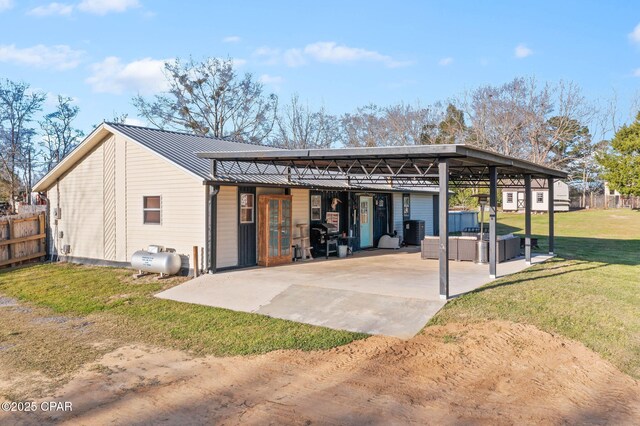 back of property with metal roof, a lawn, and fence