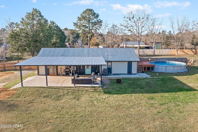 rear view of house with a fenced in pool, fence, metal roof, a yard, and a patio