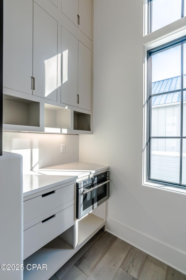 kitchen with open shelves, wood finished floors, light countertops, and white cabinets