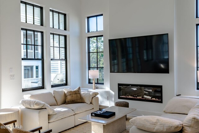 living room with a glass covered fireplace and a towering ceiling