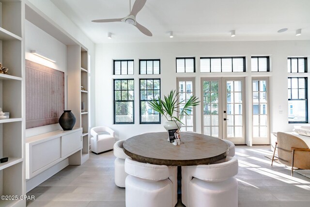 dining area featuring light wood-type flooring, ceiling fan, built in shelves, and french doors