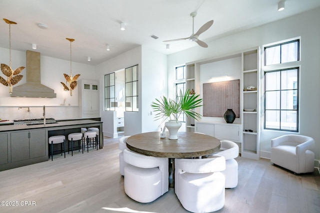 dining room with light wood-type flooring, visible vents, and a ceiling fan