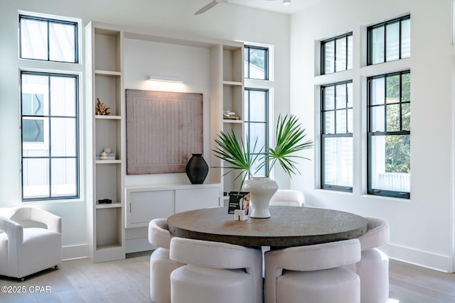 dining space featuring a ceiling fan, built in features, light wood-style flooring, and baseboards