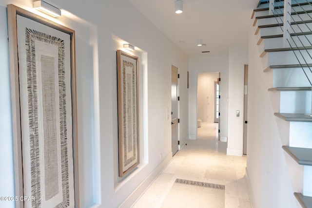 hallway with baseboards and stairway