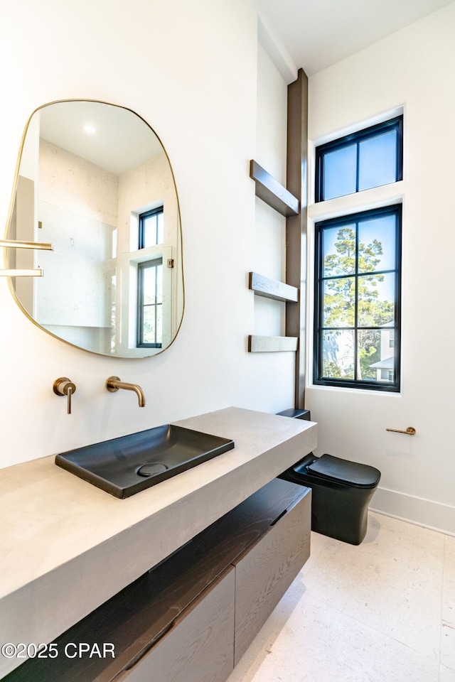 bathroom featuring plenty of natural light, vanity, toilet, and baseboards