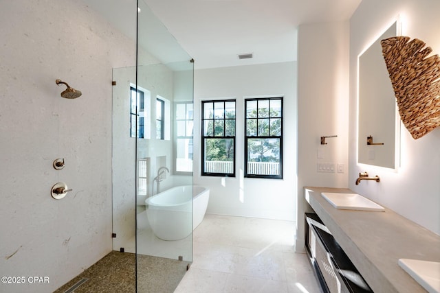 bathroom with double vanity, visible vents, walk in shower, a freestanding bath, and a sink