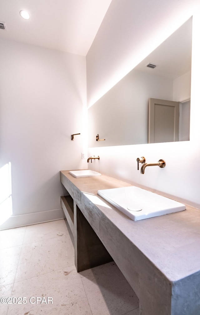 full bath featuring double vanity, baseboards, visible vents, and a sink