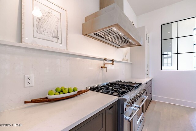 kitchen with baseboards, light countertops, light wood-type flooring, double oven range, and island exhaust hood