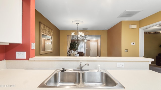 kitchen featuring light countertops, decorative light fixtures, visible vents, and a sink